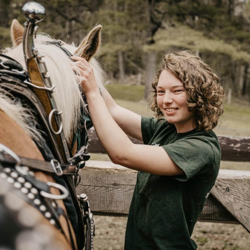 A student poses for a photo while petting a horse